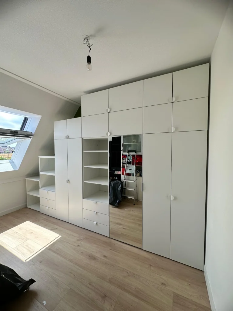 Geplaatste IKEA PLATSA kastenwand met spiegeldeur en open vakken, passend onder een schuine wand